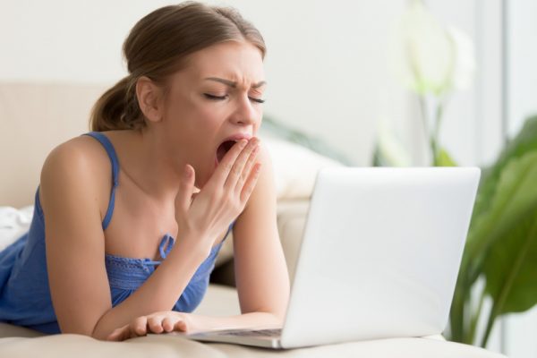 sleep deprived woman yawning in front of laptop