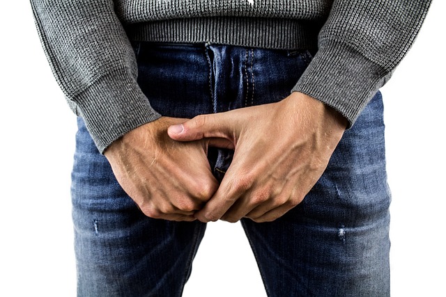 man holding the penis over jeans worried about the size